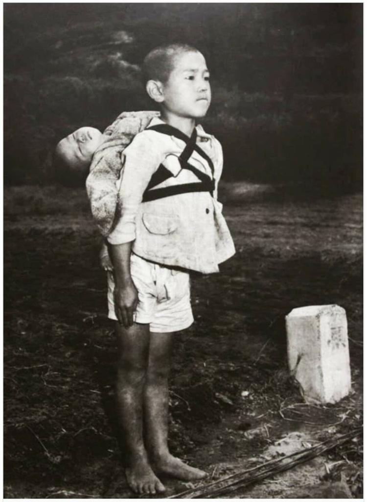 Why Japanese boy stands in front of cremation pyre, carrying dead body of his little brother ?